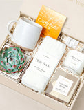 Welcome Home gift box featuring a speckled ceramic mug, fluffy white socks, a live succulent, herbal tea, and a scented candle. - Image 