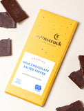 Yellow chocolate bar next to pieces of chocolate. - Image 