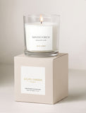 Lit Winter Forest scented candle in a glass jar resting on a minimalist beige gift box with Lula's Garden branding. - Image 