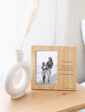 Personalized bamboo picture frame featuring engraved memorial text next to a black and white photo on a wooden table. - Image 
