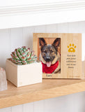 A personalized bamboo pet memorial photo frame displayed on a wooden shelf next to a small potted succulent. The frame features a photo of a German Shepherd wearing a red sweater, with a yellow paw print graphic and the name 'Lucy' printed at the bottom. - Image 