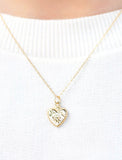 Gold heart necklace worn on top of a white sweater. - Image 