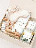 Lula's Garden gift box containing a silk sleep mask, fluffy socks, a wooden body brush, matches, and a scented candle. - Image 