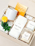Welcome home gift box featuring a ceramic mug, fluffy white socks, a succulent, herbal tea, candle, and matches. - Image 