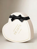 Heart-shaped white gift box with gold text reading Forever In Our Hearts and a black ribbon bow. - Image 