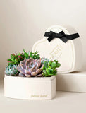 Heart-shaped planter filled with assorted green and purple succulents, featuring a black ribbon and Forever in Our Hearts text. - Image 