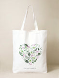 White cotton tote bag with a watercolor floral heart design of green leaves and pink flowers, and "LULA'S GARDEN" text. - Image 